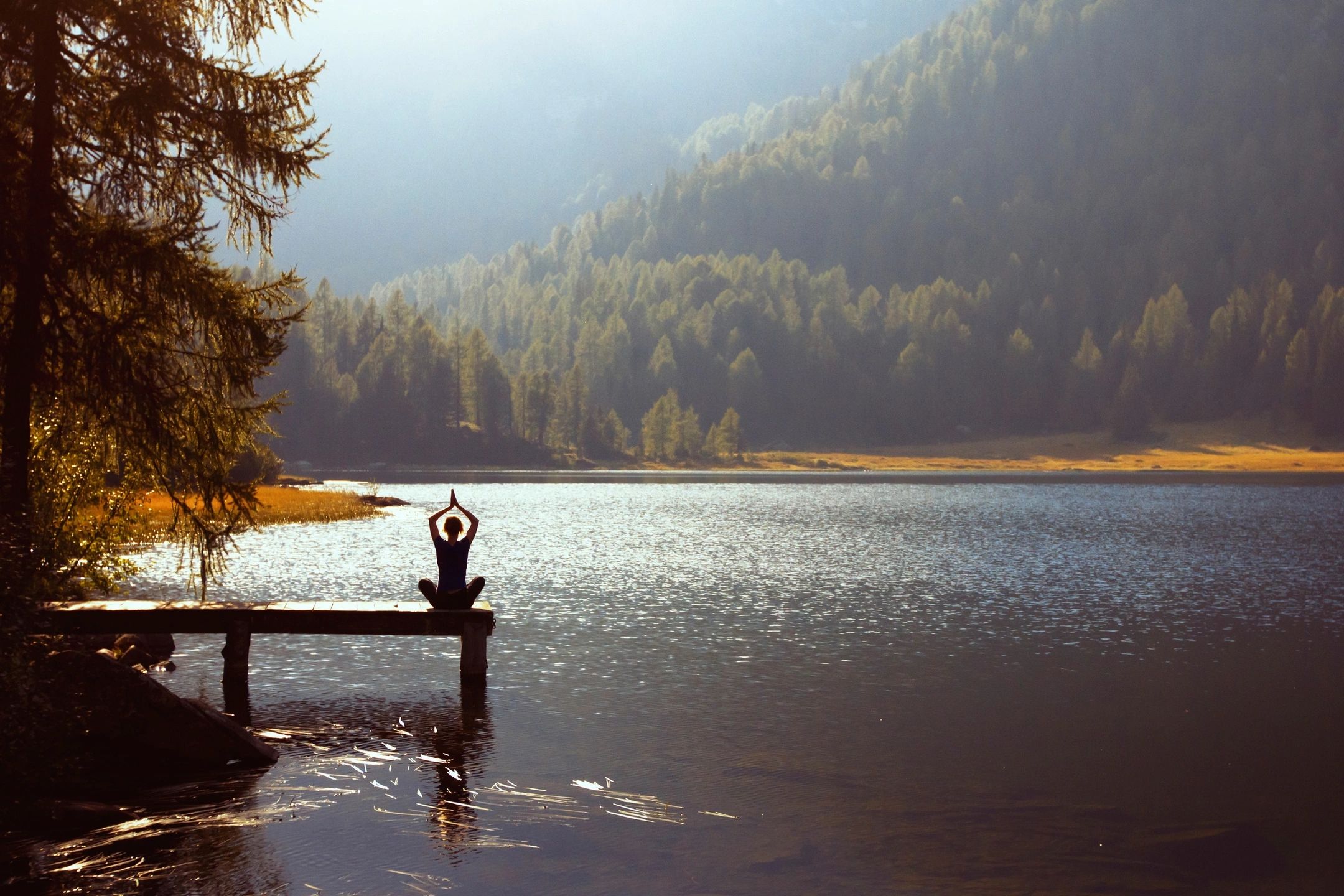 Woman meditating in lotus pose by the ocean